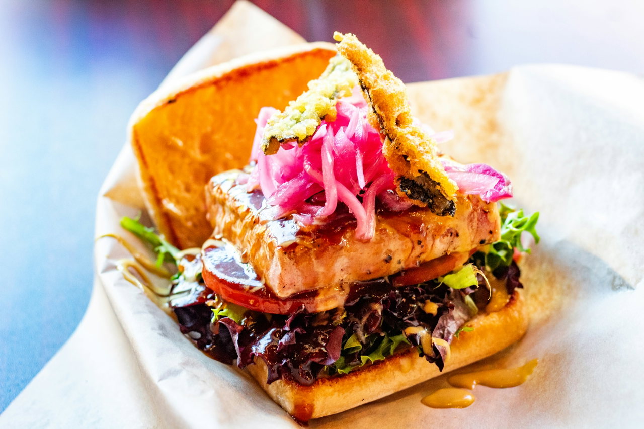 Brötchen mit gebratenem Fisch, Salat und eingelegten roten Zwiebeln