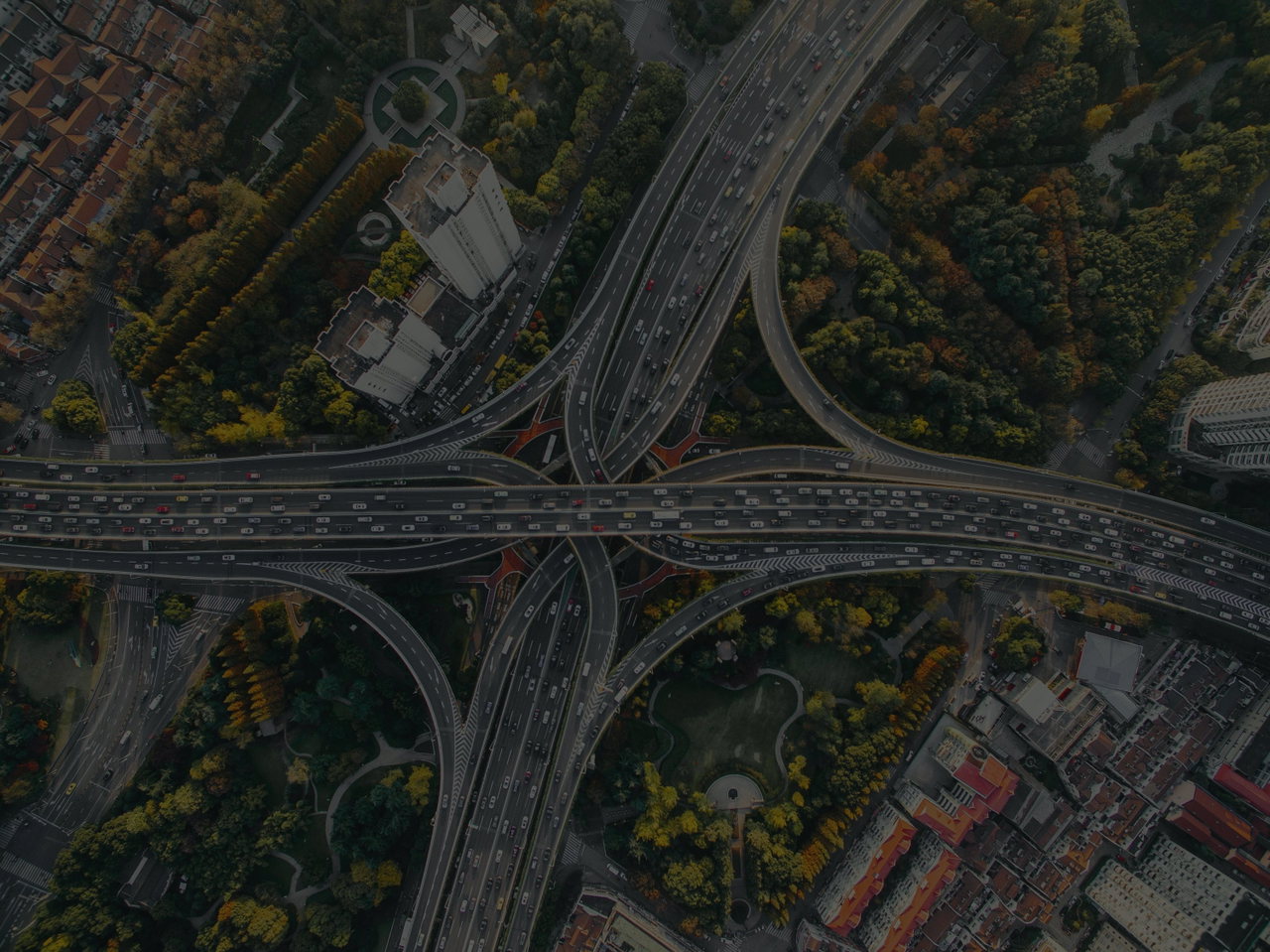 Luftaufnahme eines Autobahnkreuzes, dazwischen Bäume in Herbstfarben