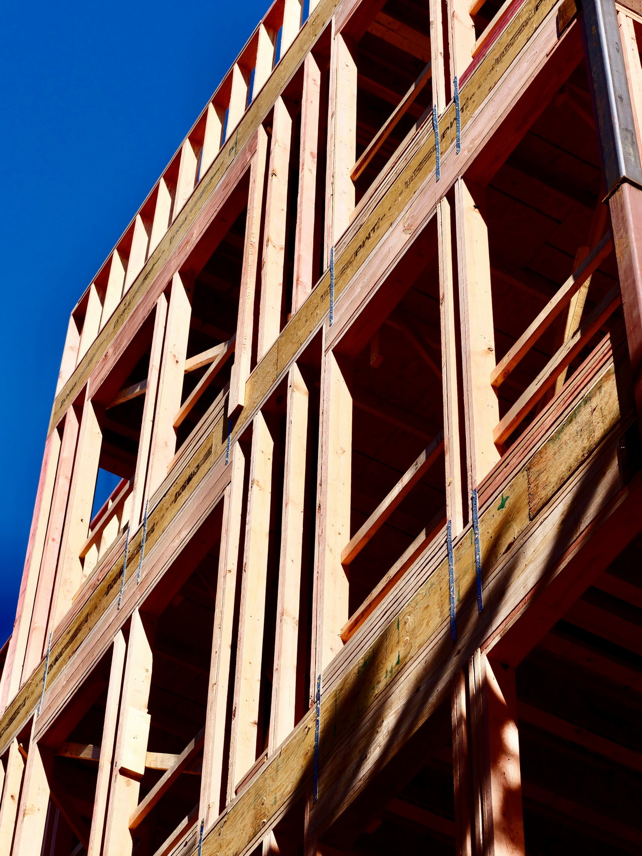 Holzrahmenbau eines mehrgeschossigen Gebäudes im Rohbau vor blauem Himmel
