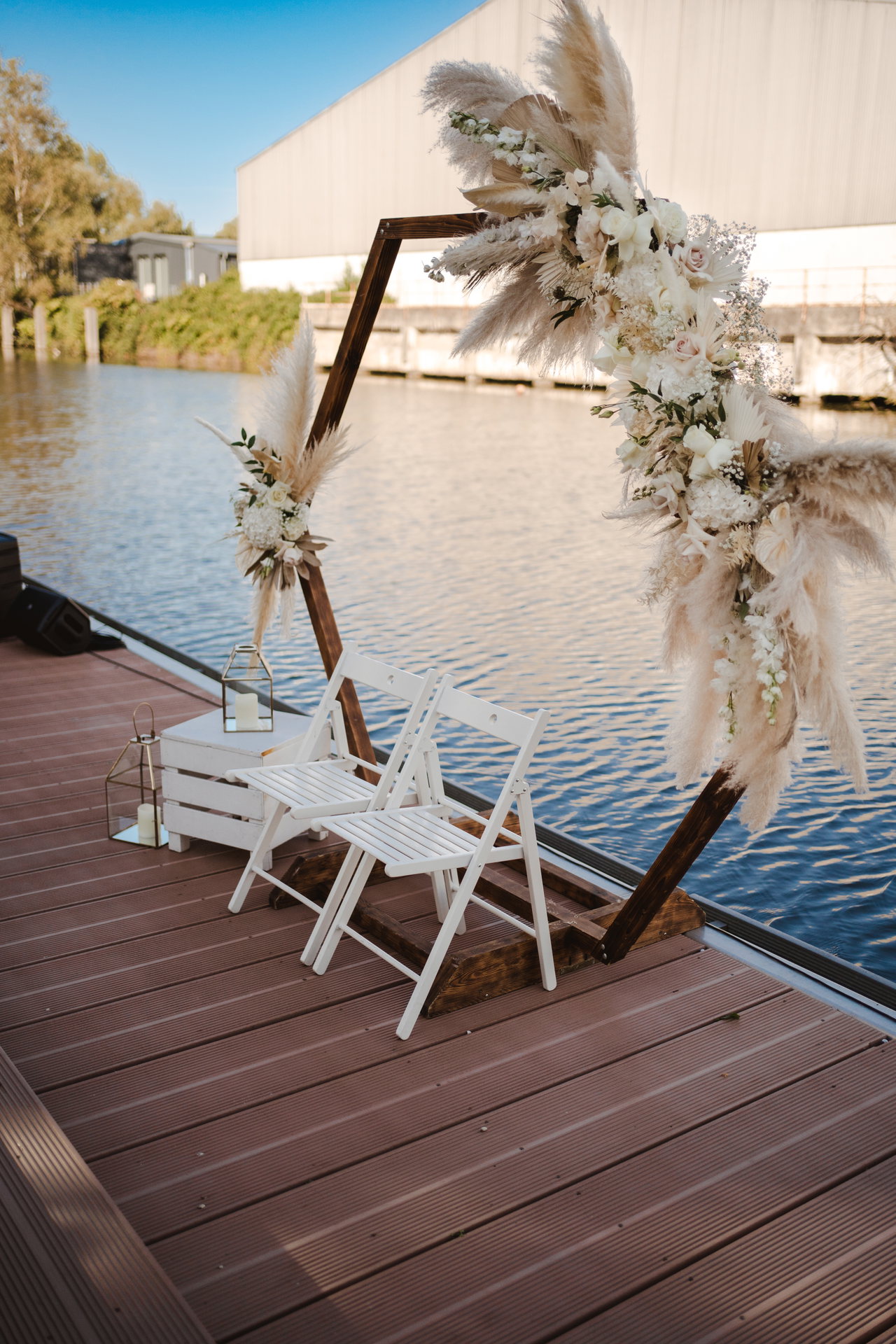 Sechseckiger Holzbogen mit Trockenblumen vor dem Wasser