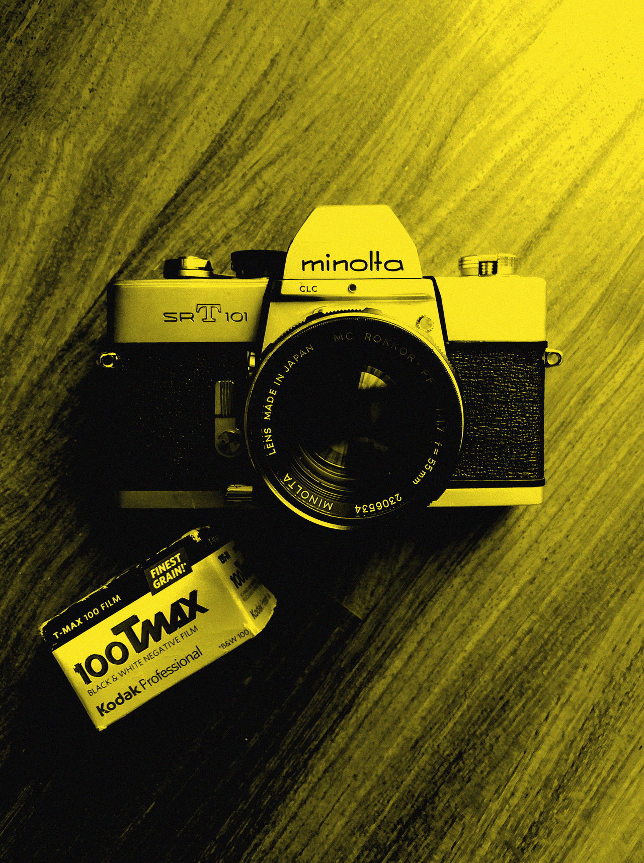 Minolta-Spiegelreflexkamera mit Filmdose auf einem Holztisch, Gelb-Duplex