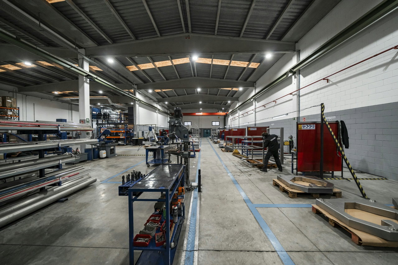 Helle, aufgeräumte Produktionshalle mit Werkbänken, Materiallager und markierten Wegen.