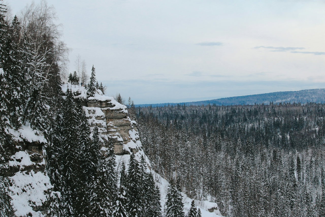 Verschneite Felsklippen und Tannenwald mit weitem Blick über die winterliche Landschaft