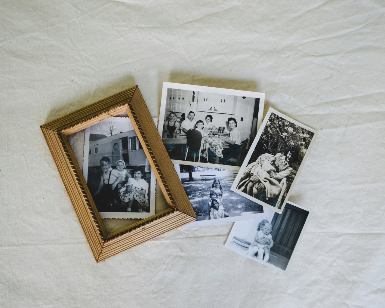Ein Bilderrahmen mit altem Familienfoto, daneben weitere alte Fotos