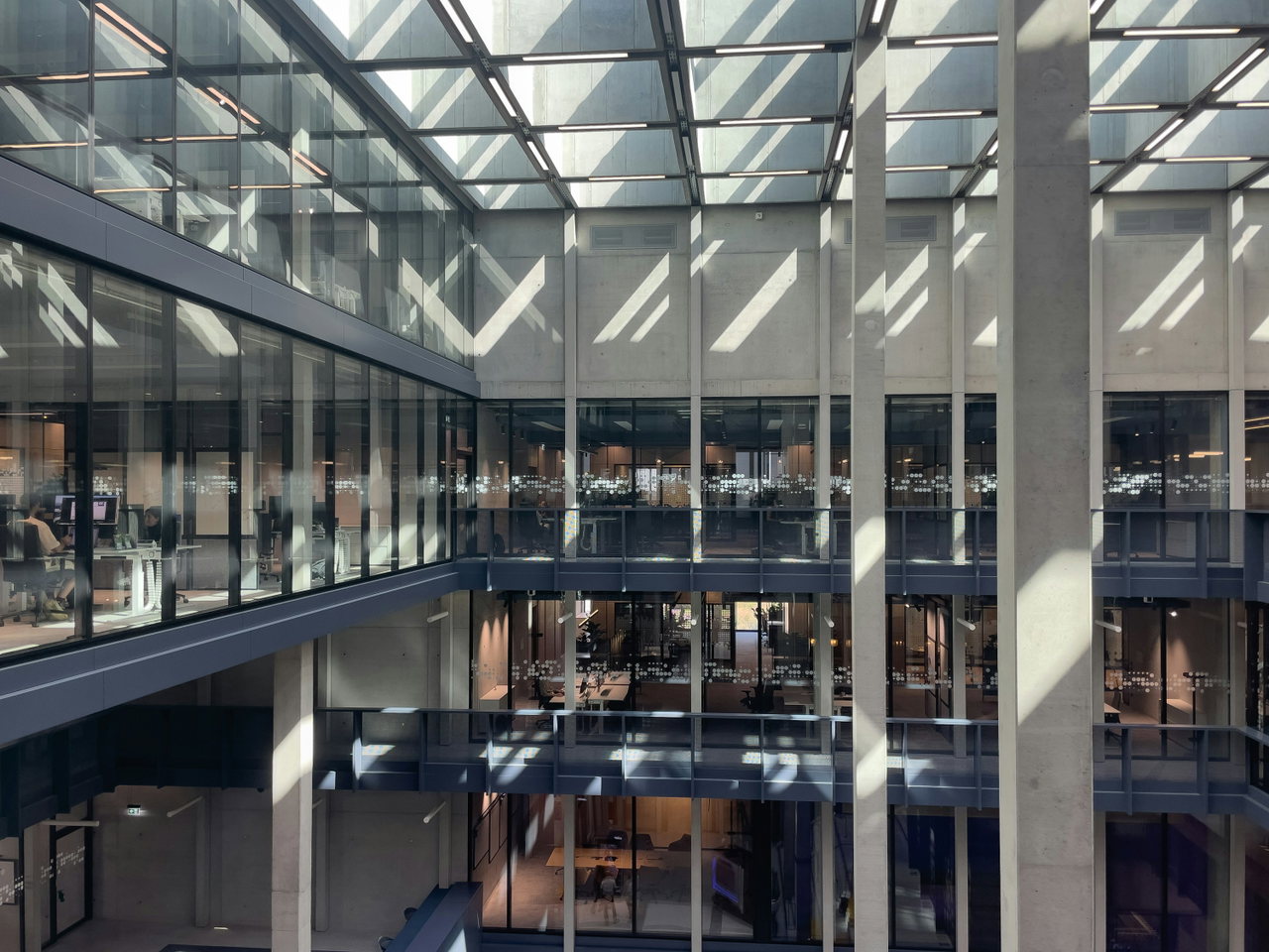 Heller Atrium eines Verwaltungsgebäudes mit Glasdach, Galerien und einfallendem Tageslicht