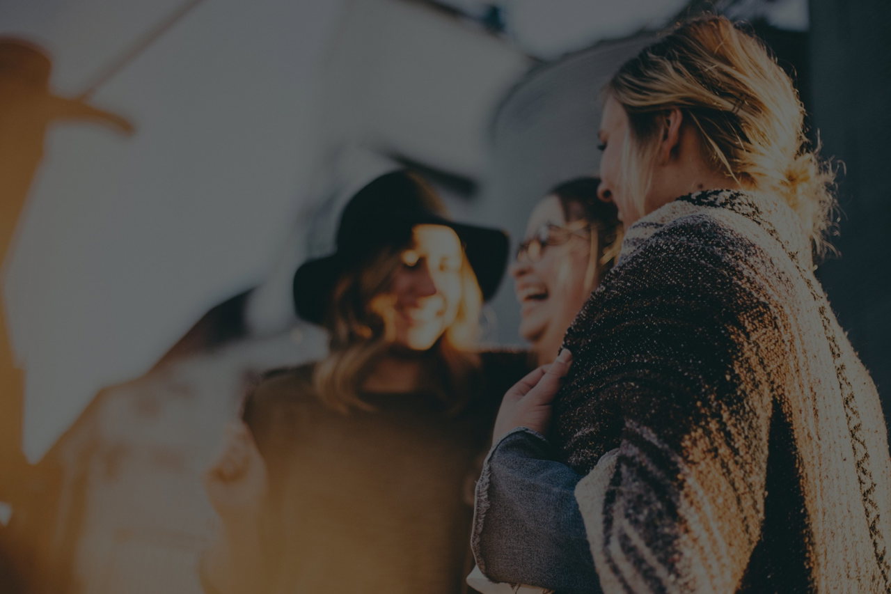 Drei Frauen stehen lachend beieinander
