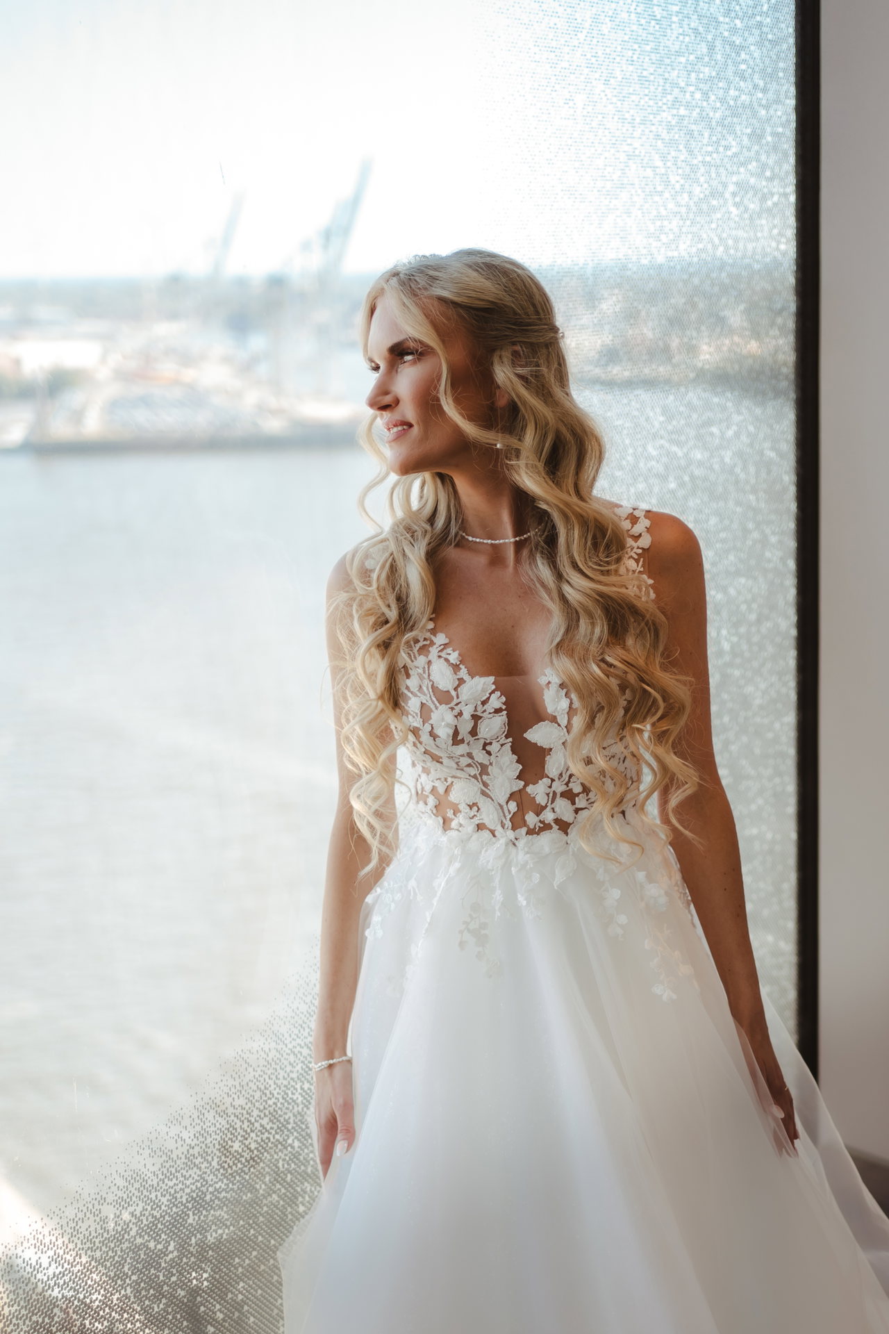 Elain im Brautkleid am Fenster, dahinter der Hafen