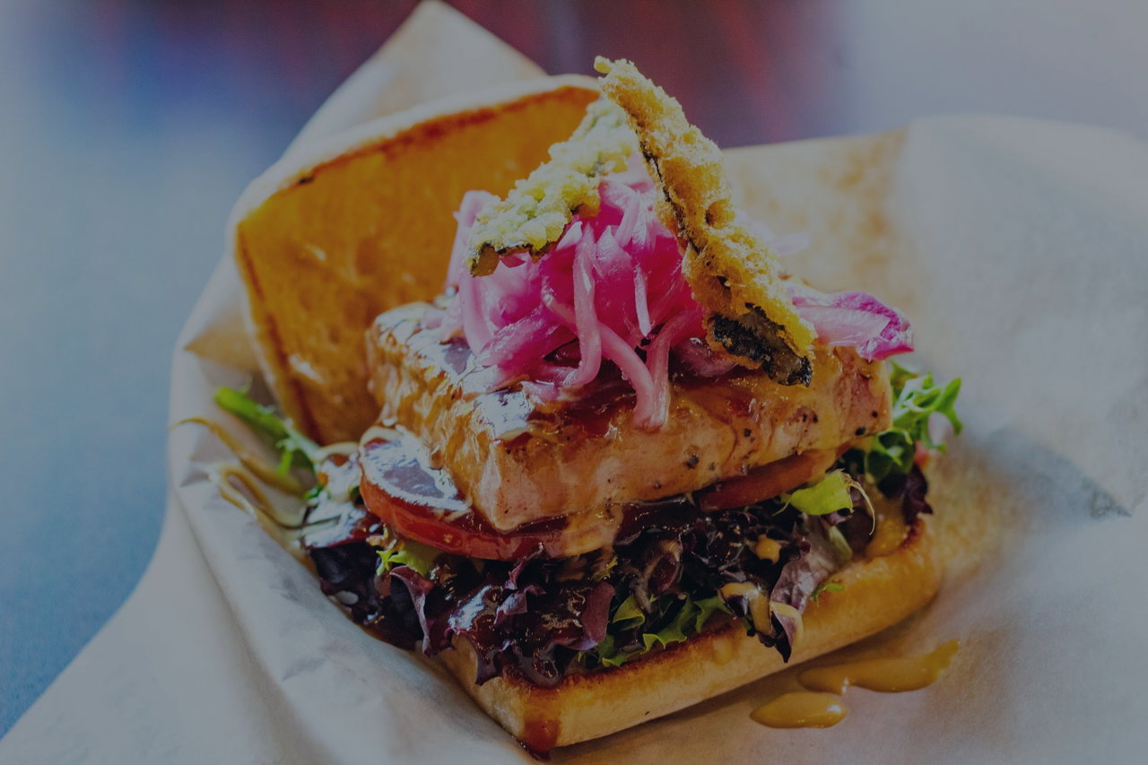 Brötchen mit gebratenem Fisch, Salat und eingelegten roten Zwiebeln