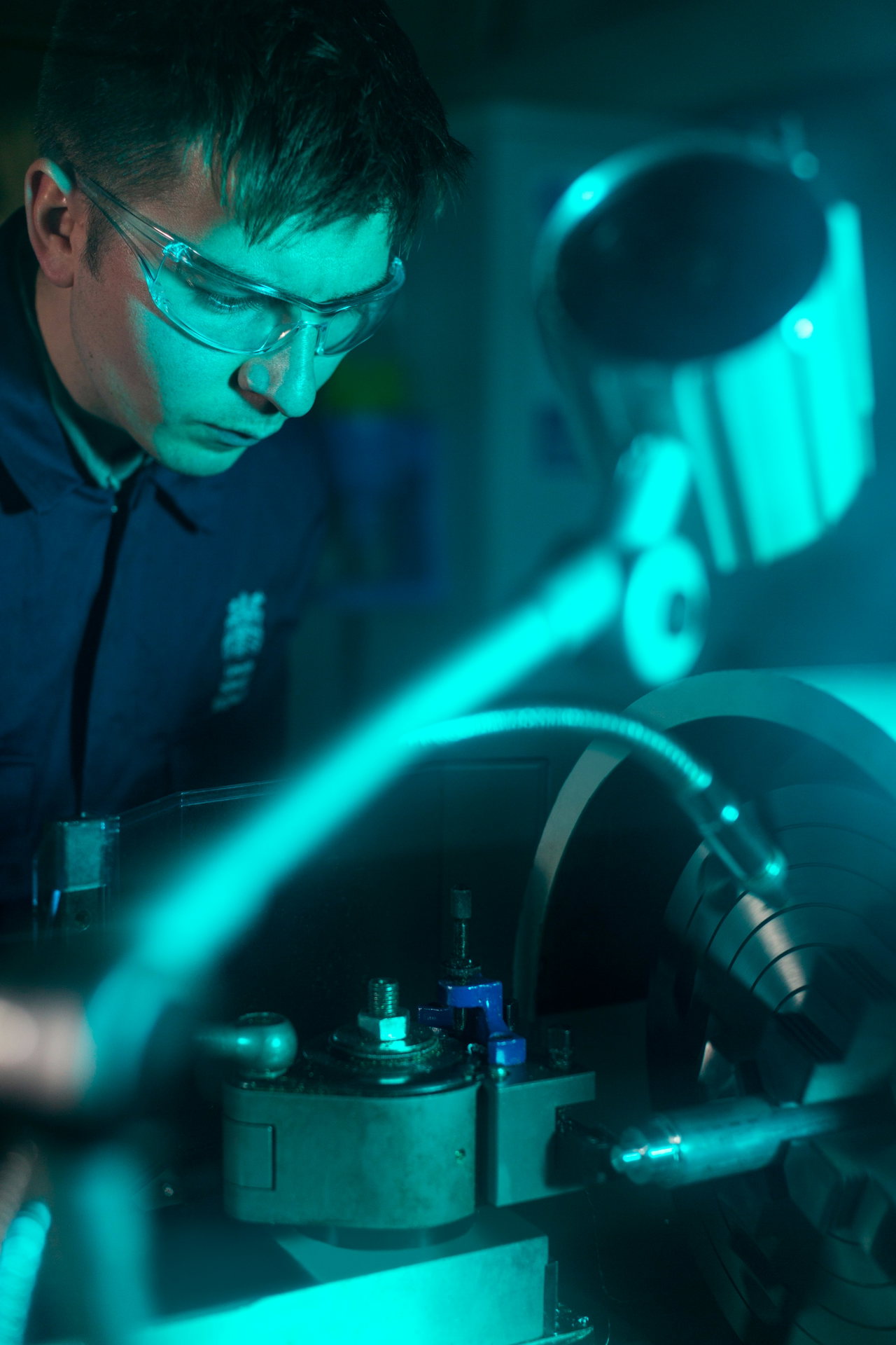 Junger Auszubildender mit Schutzbrille arbeitet konzentriert an einer Drehmaschine.