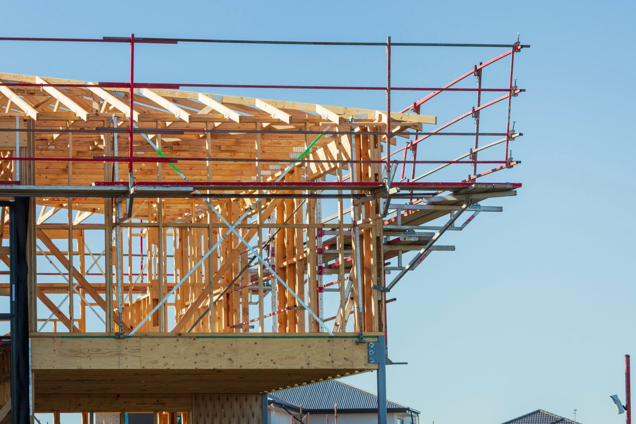 Holzrahmenbau mit Gerüst und Dachsparren vor hellem Himmel