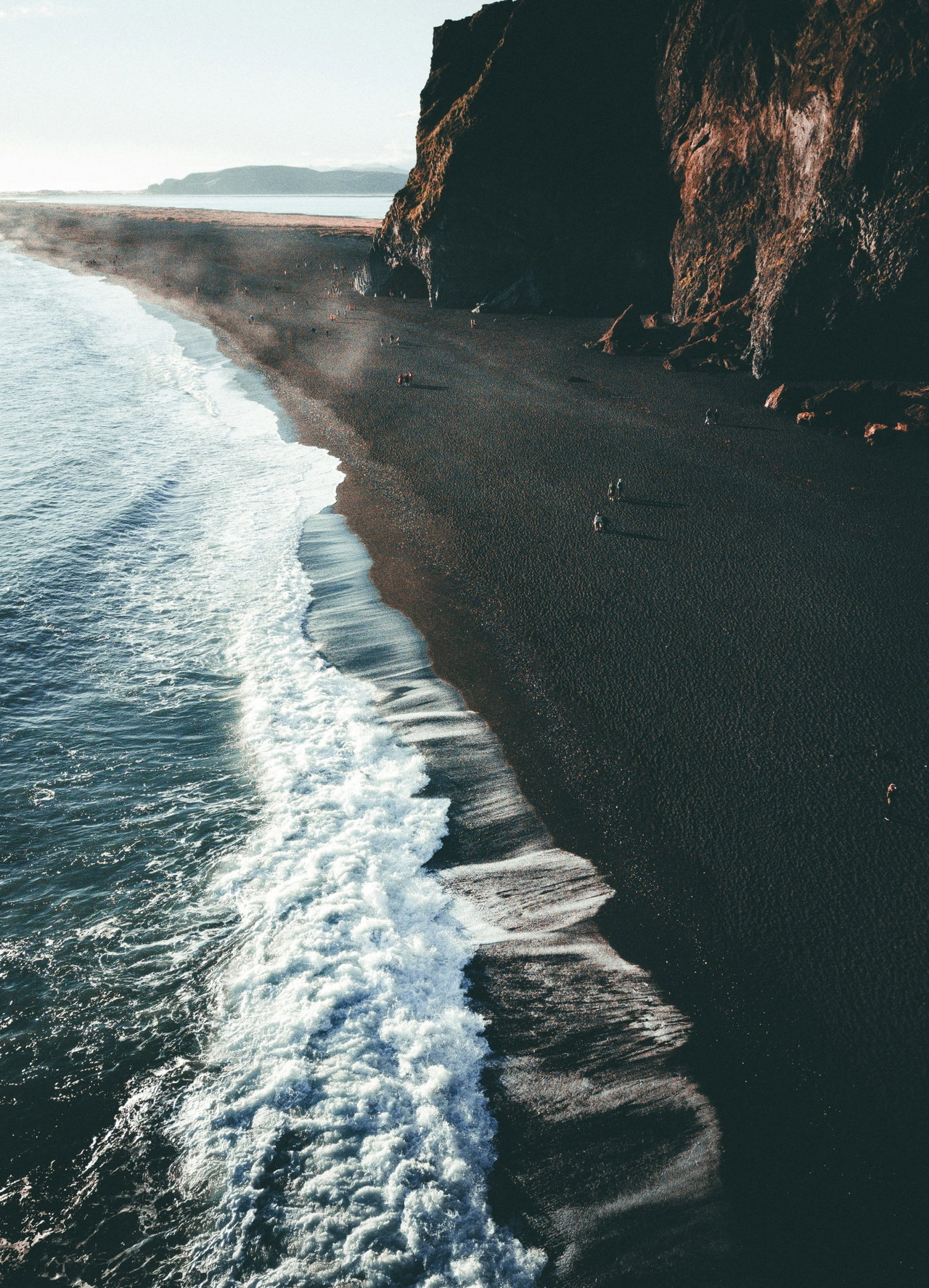 Steilküste über einem schwarzen Sandstrand