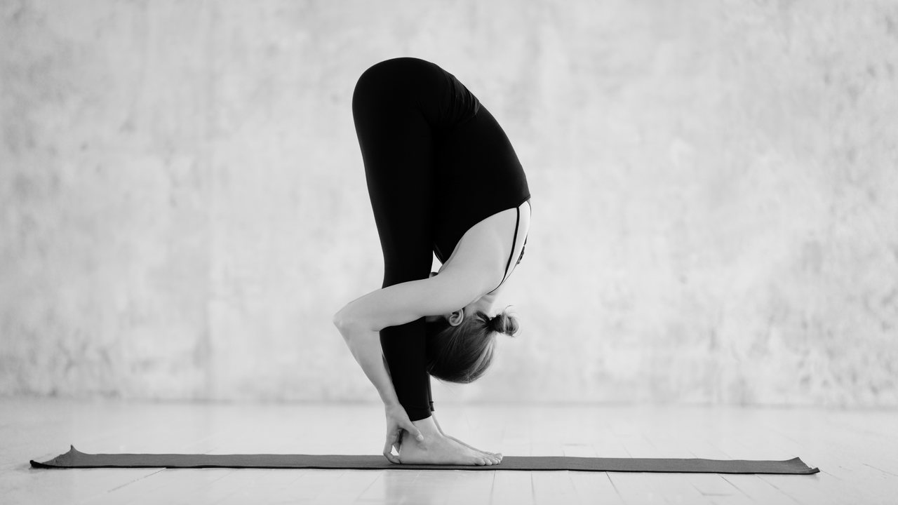Dieses Bild zeigt eine Frau in der Yoga-Pose "stehende Vorbeuge".