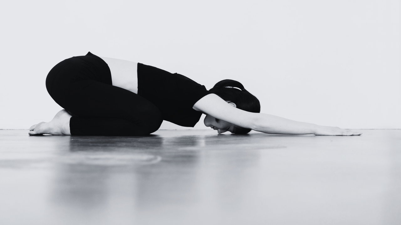 Dieses Bild zeigt eine Frau auf einer Yoga-Matte in der Stellung des Kindes.