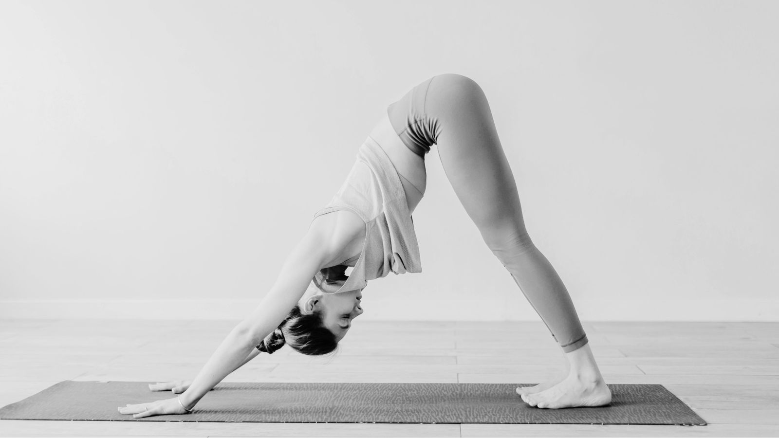 Dieses Bild zeigt eine Frau auf der Yoga-Matte in der Stellung des herabschauenden Hundes.