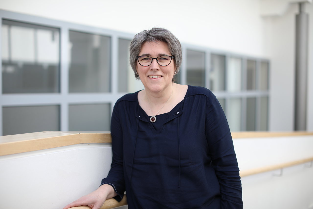 Anke-Zander-in-schwarzem-Oberteil-steht-vor-einem-Fenster